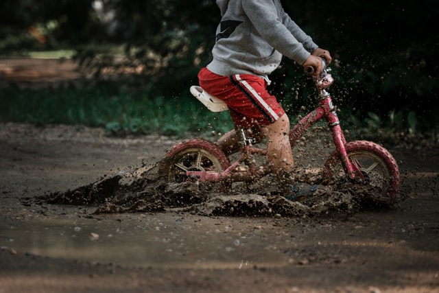 child on bike in muddy water